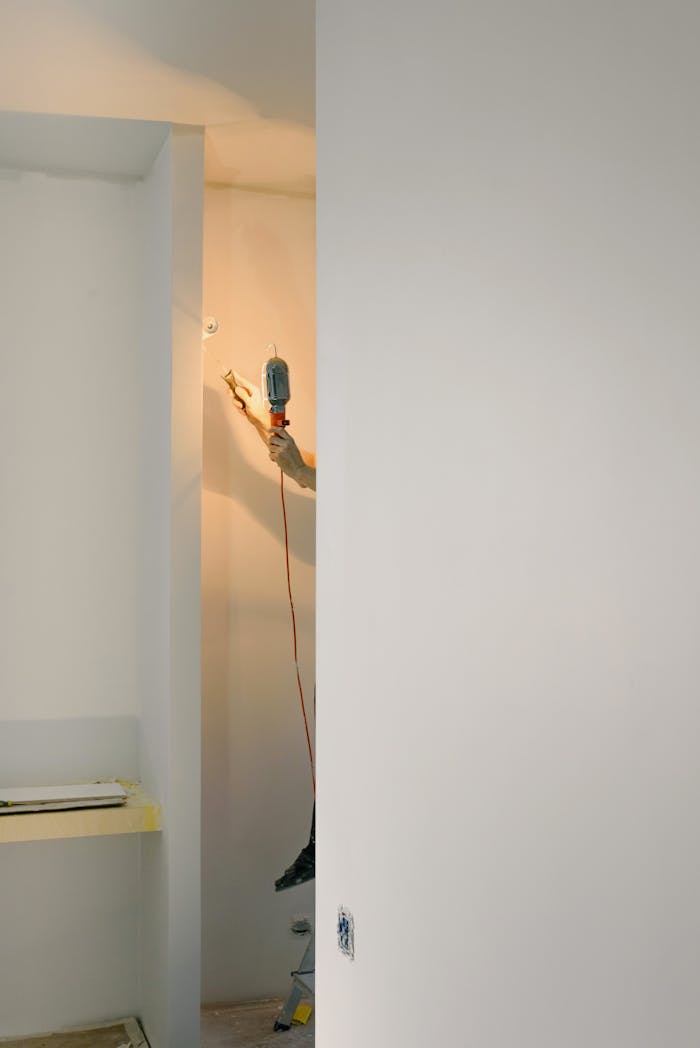 gallery-01 Crop faceless handyman standing on ladder while holding lamp and working in room